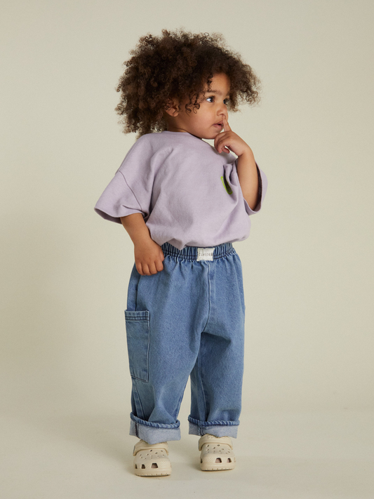 Second image of EMERSON DENIM BABY TROUSER: loose-fitting unisex pants crafted from organic cotton denim, featuring an elastic waistband and side pockets, shown against a white background.