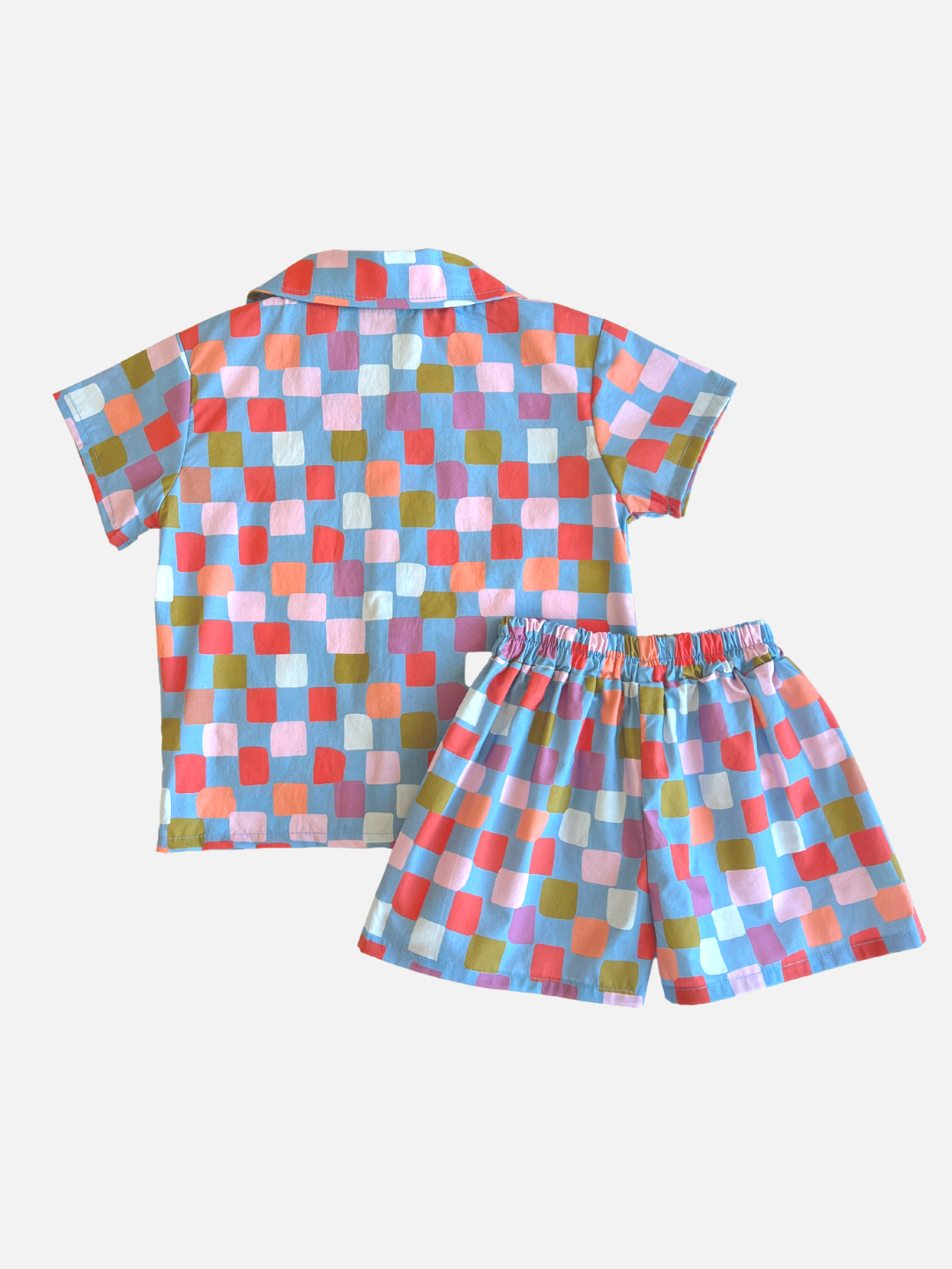 A kids' shirt and shorts set in a pattern of red, orange, pink, lilac and green squares on a blue background, back view