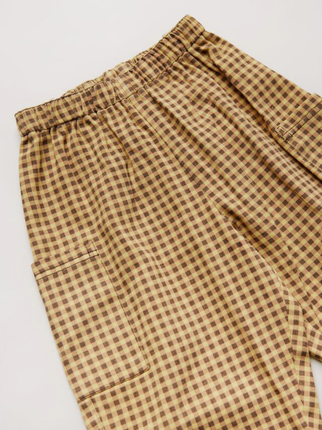 The EMERSON OCHRE GINGHAM TROUSER features brown and beige plaid, an elastic waistband, and a side pocket, shown laid flat on a light surface.