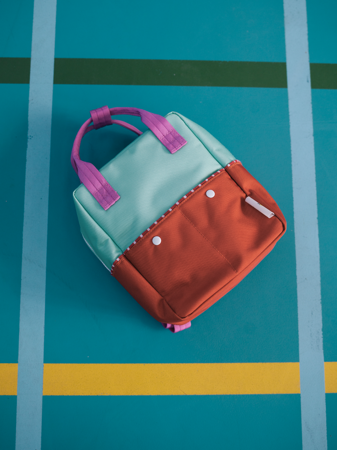 Towel Green | Towel Green Colourblocking backpack is laid flat on a table. 