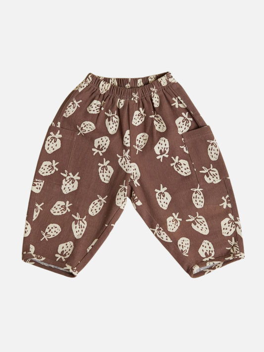 Image of The EMERSON CHOC STRAB TROUSER are brown children's pants featuring an elastic waistband, two pockets, and a white strawberry print pattern.