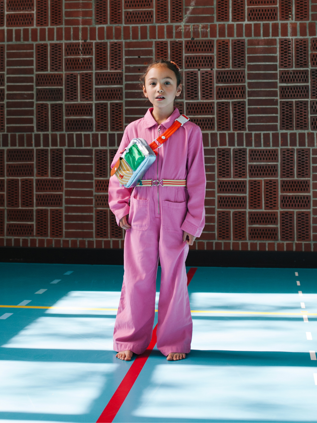 Metallic Blue | A child is wearing a Metallic Blue Bike Bag with a pink jumpsuit.