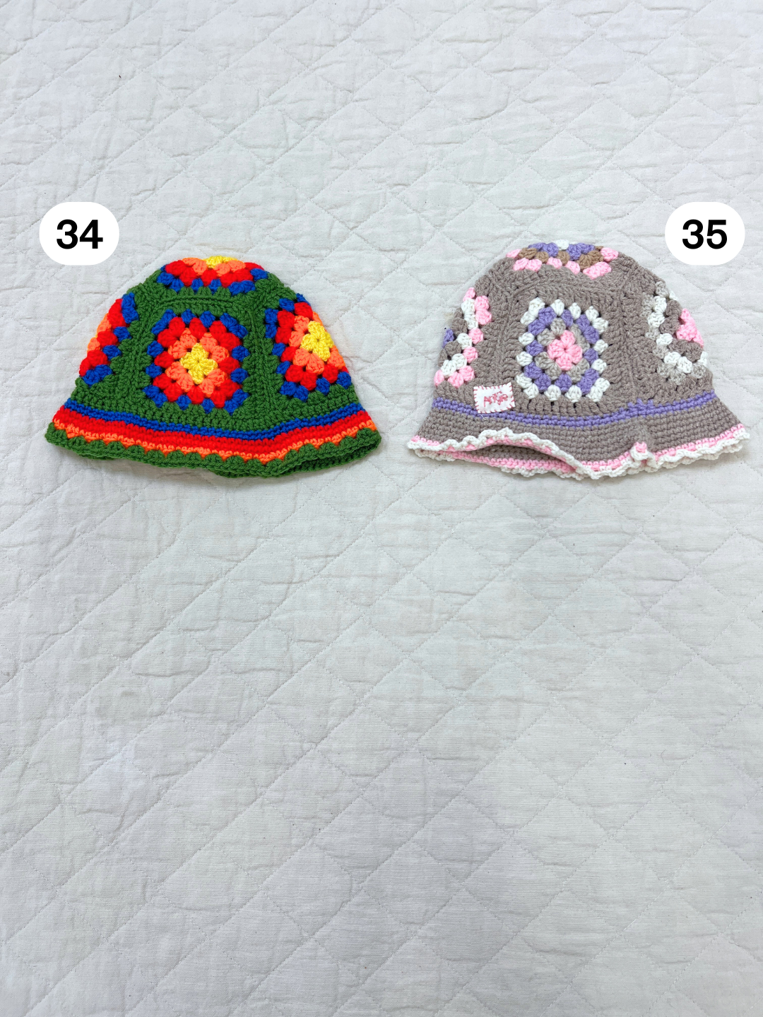 A hand-made CROCHETED BUCKET HAT 1-3Y in multicolored (#34) is displayed on a quilted white surface, inspired by the vibrant styles of South Africa.