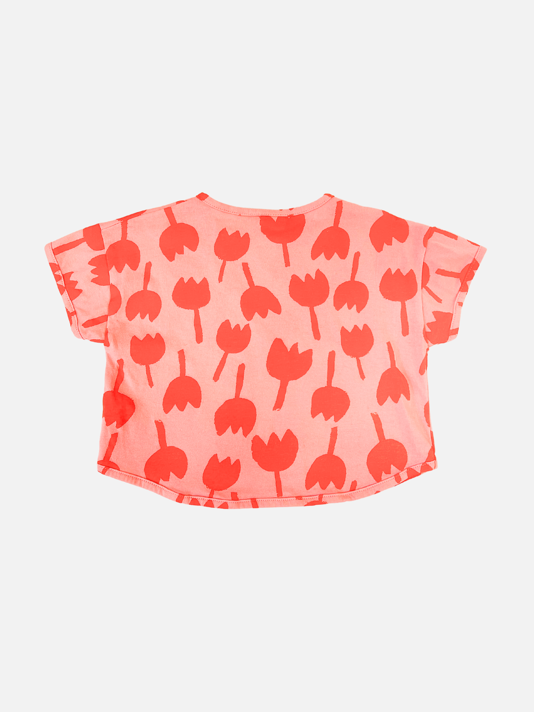 Back view of kids tulip tee with short sleeves in coral pink with an all-over print of dark pink graphic tulip shapes.