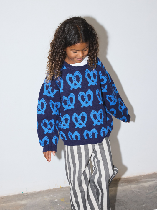 Second image of Blue | A navy blue long-sleeve knit sweater with a repeating light blue pretzel pattern, laid flat against a light gray background.