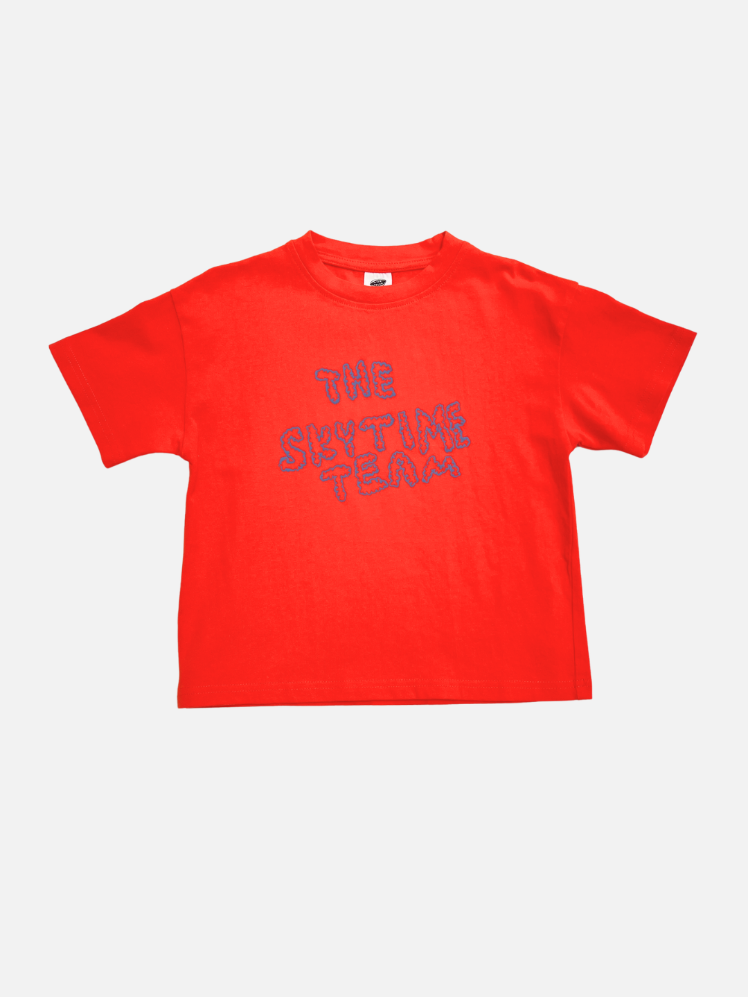 The SKYTIME TEE is a red, artist-designed short-sleeve t-shirt featuring "THE SKYTIME TEAM" in blue outlined letters on the front, shown on a plain white background.