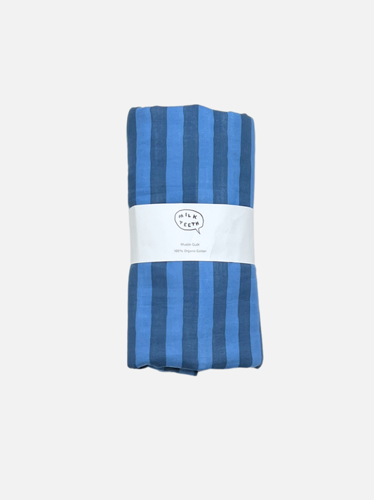 Image of Blue Stripe | A medium blue and darker blue striped cotton quilt is shown rolled up with a white Milk Teeth label around the middle.