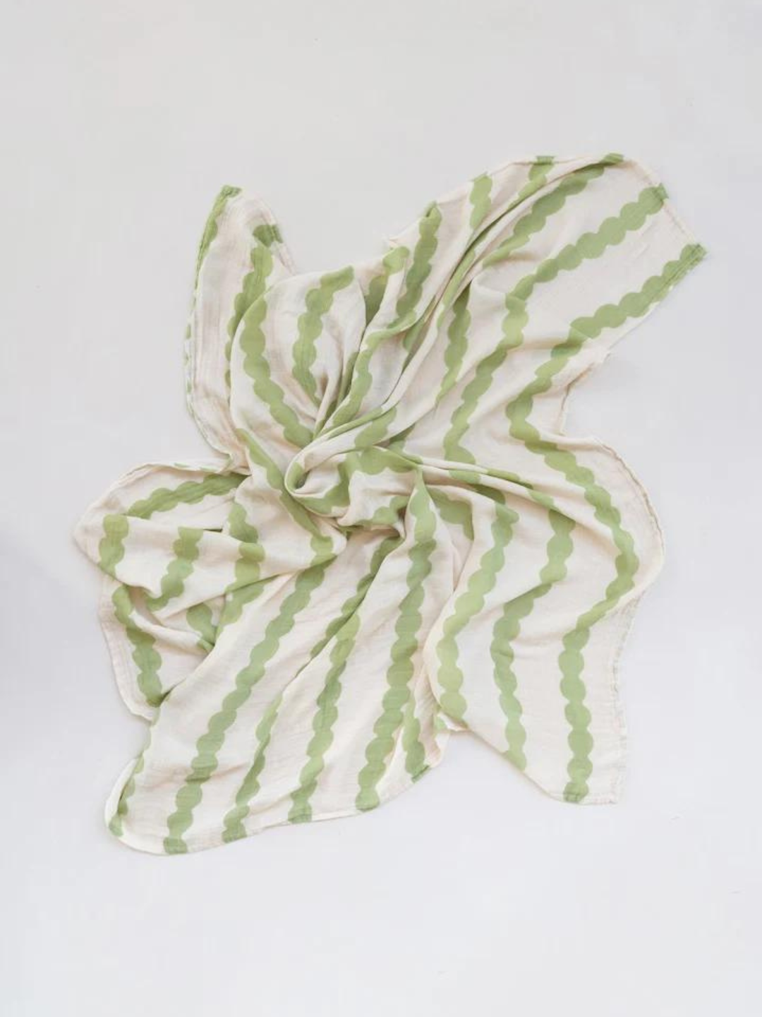 Edamame | The ORGANIC BAMBOO SWADDLE WRAP, featuring a light-colored design with green wavy stripe patterns, is spread out on a white surface.