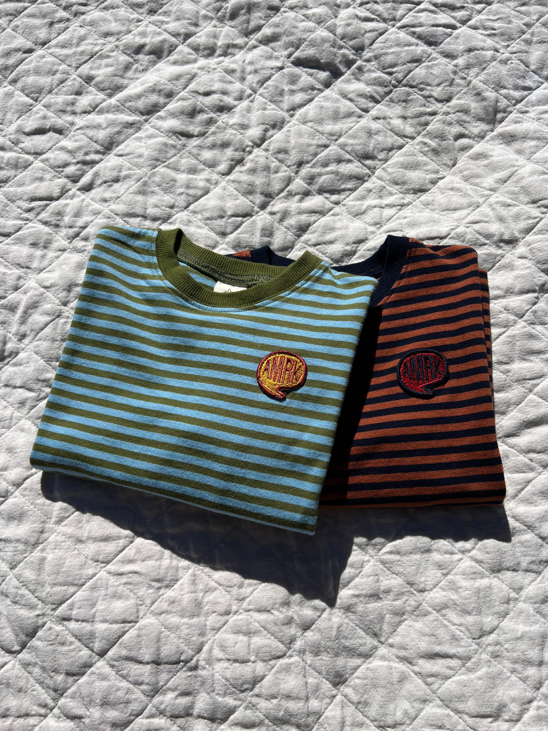 Comma Striped Longsleeve in Sky/Olive and Rust/Navy laid on blankets