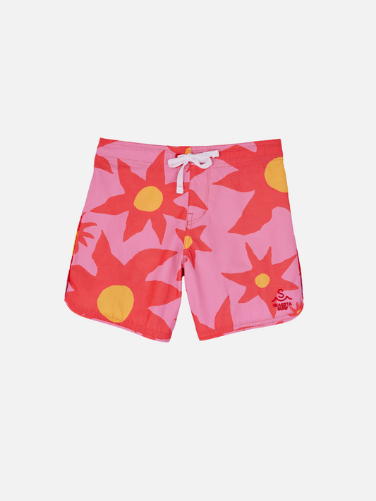 Image of A front view of the kid's Siesta Scallop Retro Flare Boardshort, highlighting the adjustable waistband white, Saesta Swim logo on the left in pink. The design features large red flowers. 