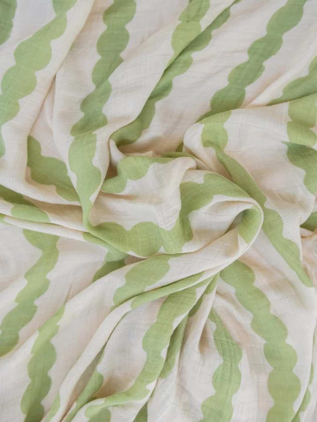 Edamame | A close-up image of crumpled fabric featuring a light green and white wave pattern, reminiscent of the cozy ORGANIC BAMBOO SWADDLE WRAP.