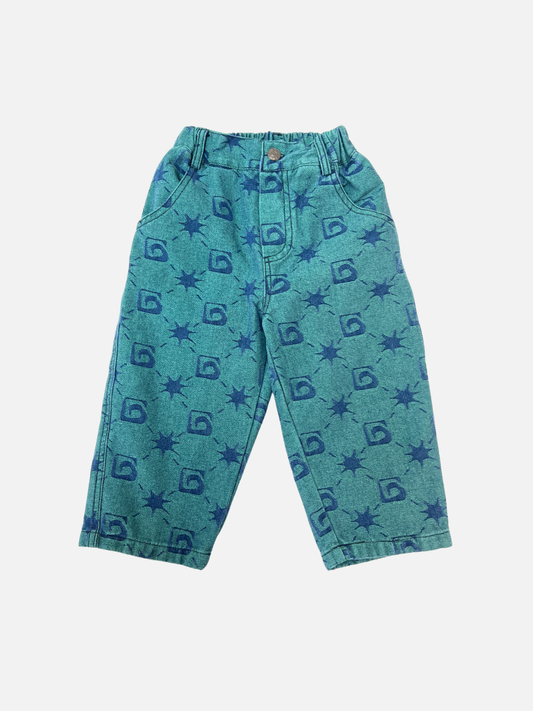 Image of TRELLIS JEANS: Teal children’s pants from the Milk Teeth collection, made from soft denim jacquard with an elastic waistband and blue geometric and sunburst patterns.