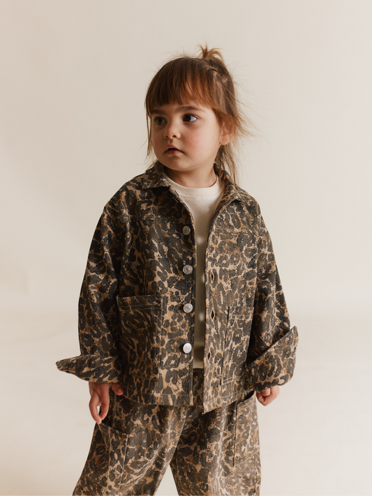 Second image of The FEN LEOPARD JACKET is an oversized piece with long sleeves, showcasing a chic gray and brown leopard pattern. Made from organic cotton, it features a convenient front button closure.