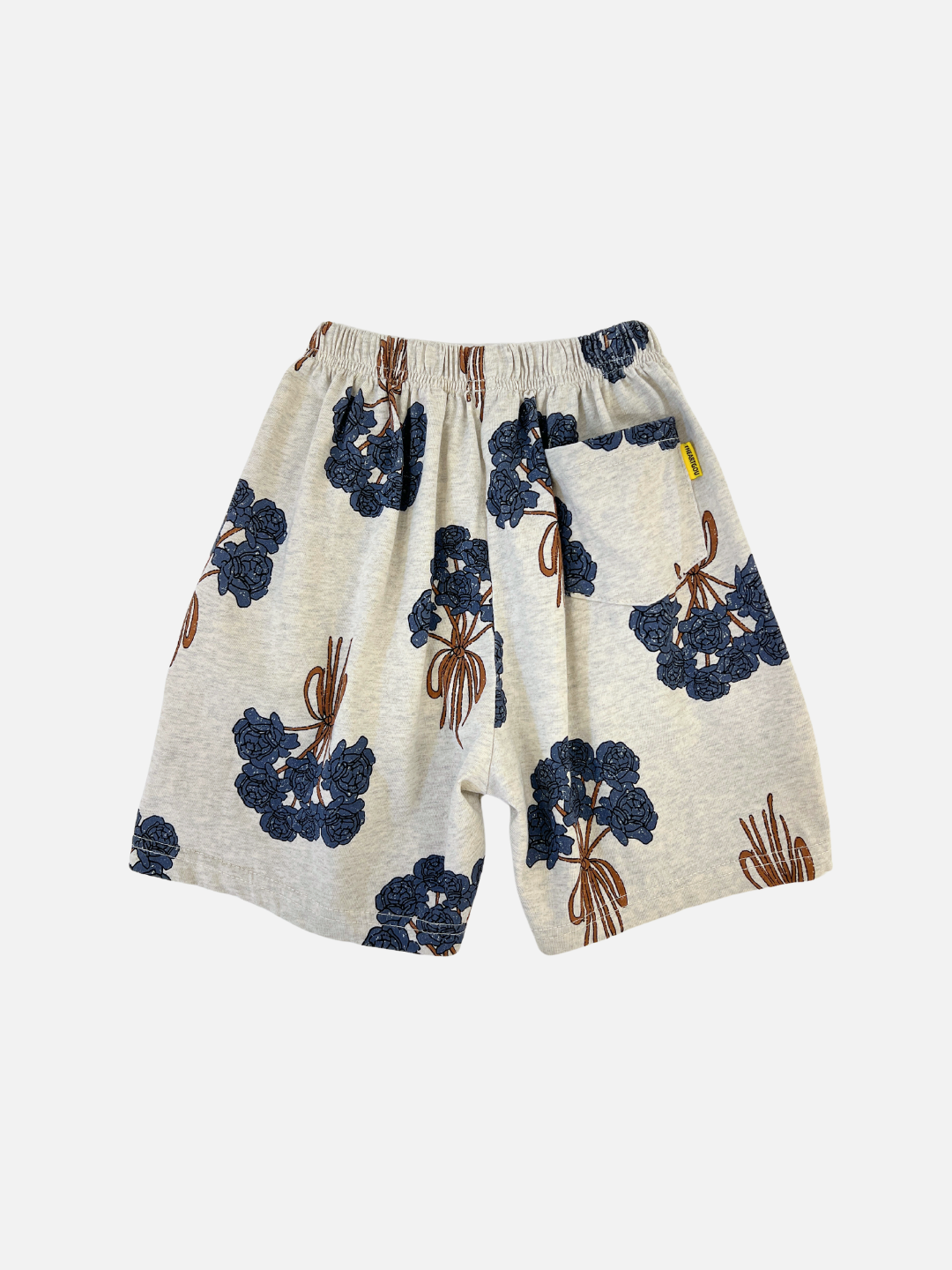 Back view of the kids' Bouquet Shorts. warm gray cotton fabric with an all-over navy roses bouquet print. Back pocket on the right side.