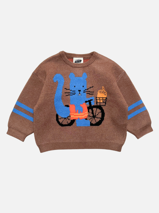 Image of A brown knit sweater for kids featuring a blue squirrel riding a black bicycle with an acorn in the basket. The sleeves have two blue stripes, and the sweater is shown flat against a light gray background.