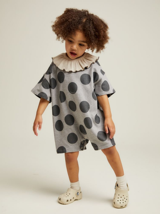 Second image of The OPAL MARL SPOT ROMPER is a gray baby romper featuring large black polka dots, snap closures at the crotch, and a round neckline.