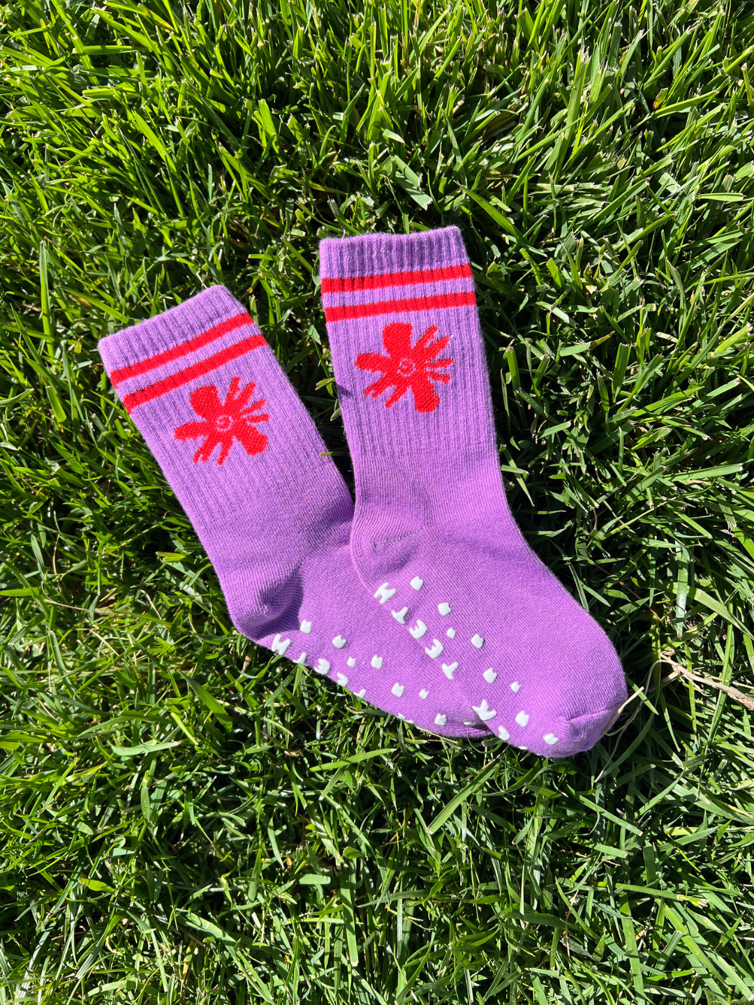 Swirl Flower | Purple socks with red star designs on grass