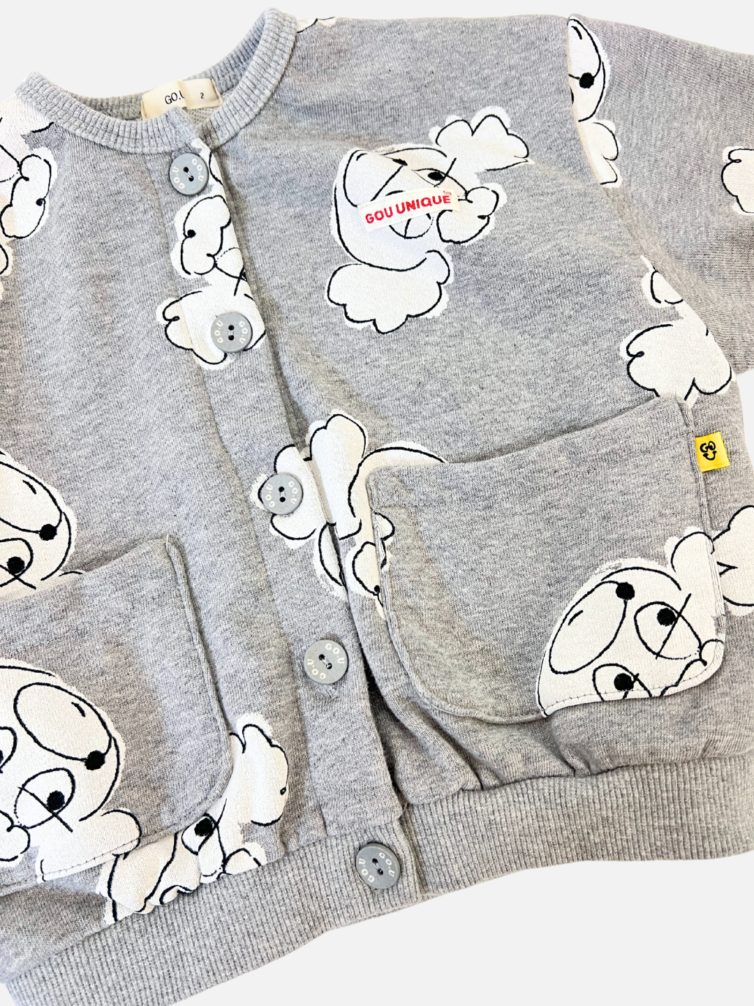 Grey | POODLE BUTTON DOWN SWEATSHIRT: A gray baby cardigan with a whimsical cartoon bear design, two front pockets, and a small yellow side tag.