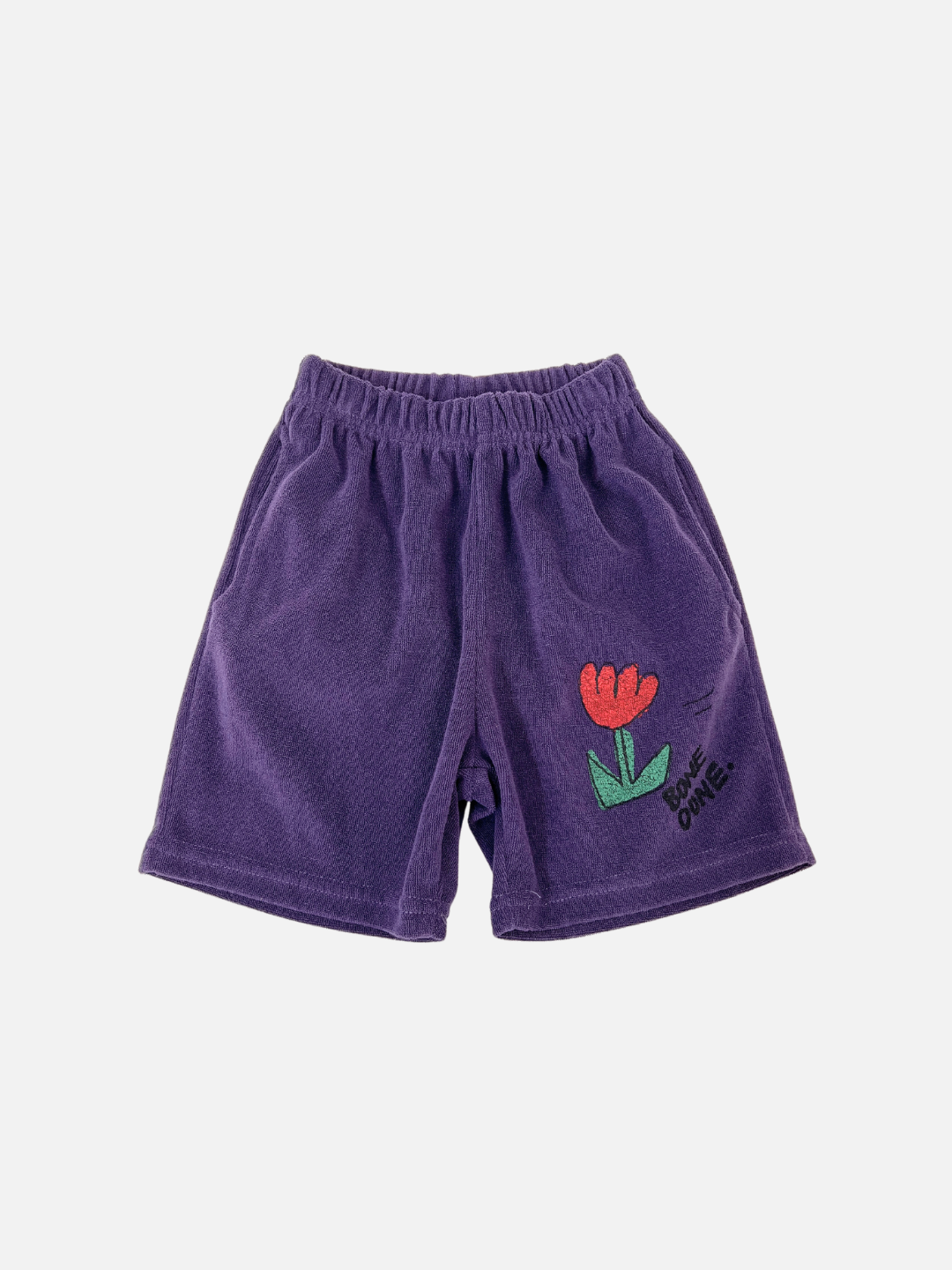 The TULIP TERRY SHORTS are purple cotton shorts featuring an elastic waistband and a flower graphic near the hem. They offer a slouchy fit, ideal for casual days. This fun and comfortable style is from a popular Korean kids' brand.