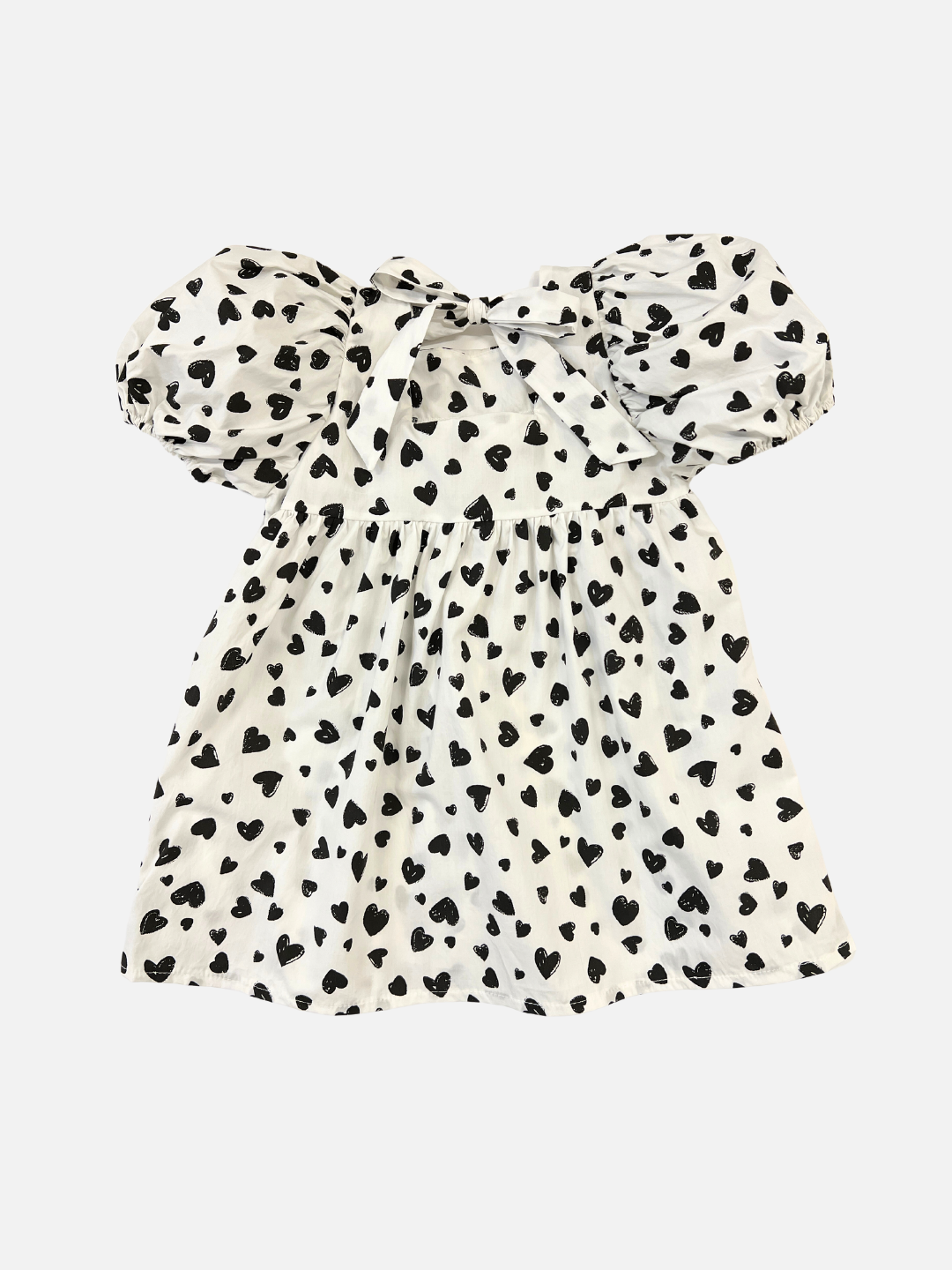 Back view of a kids' puff-sleeved dress in a pattern of black hearts on a white background, bow tied at the neck