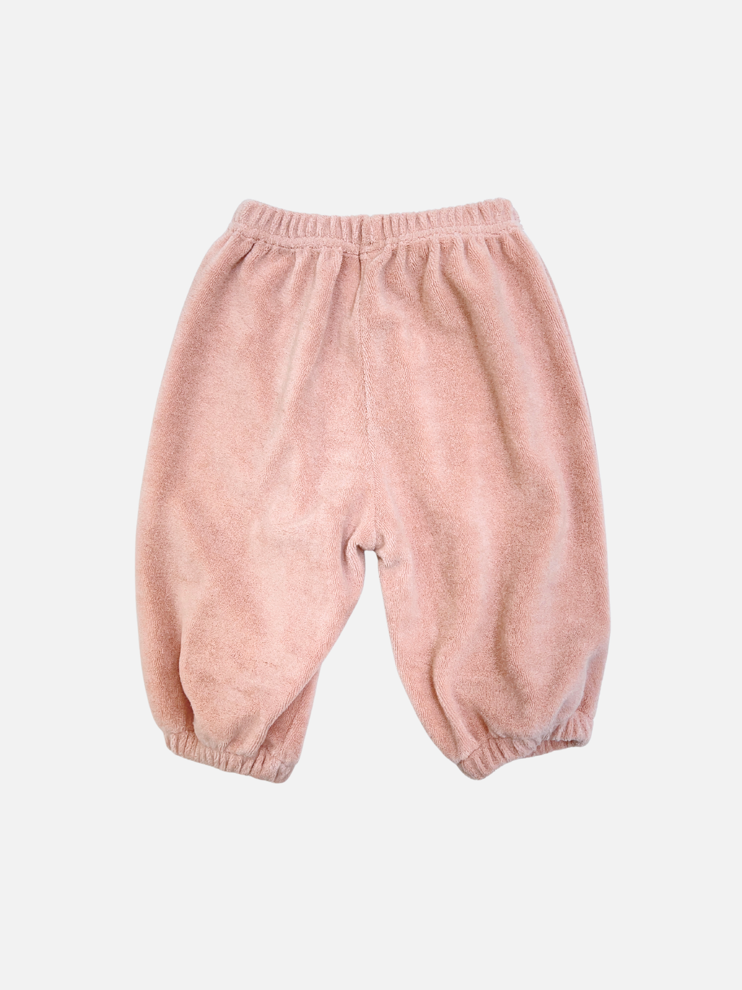 Pink | The BABY TERRY JOGGER features light pink cotton terry, an elastic waistband and cuffs, and is inspired by a Korean baby brand. These cozy jogger pants for babies are shown on a white background.