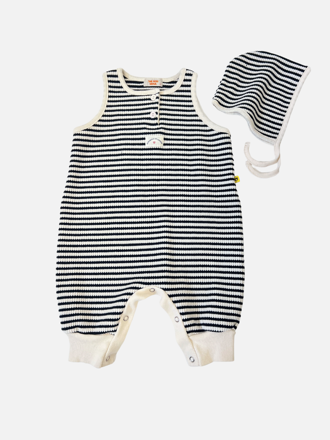 Navy | The STRIPE WAFFLE ROMPER SET, in navy, is a sleeveless baby jumpsuit made of soft waffle cotton. It features a button closure at the front, ankle snaps, and includes a matching bonnet.