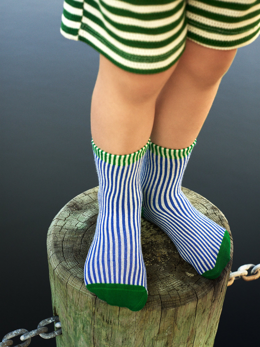 Second image of Cobalt | Kids socks in narrow blue and white vertical stripes with kelly green toe, heel, and green stripes at ankle cuff.