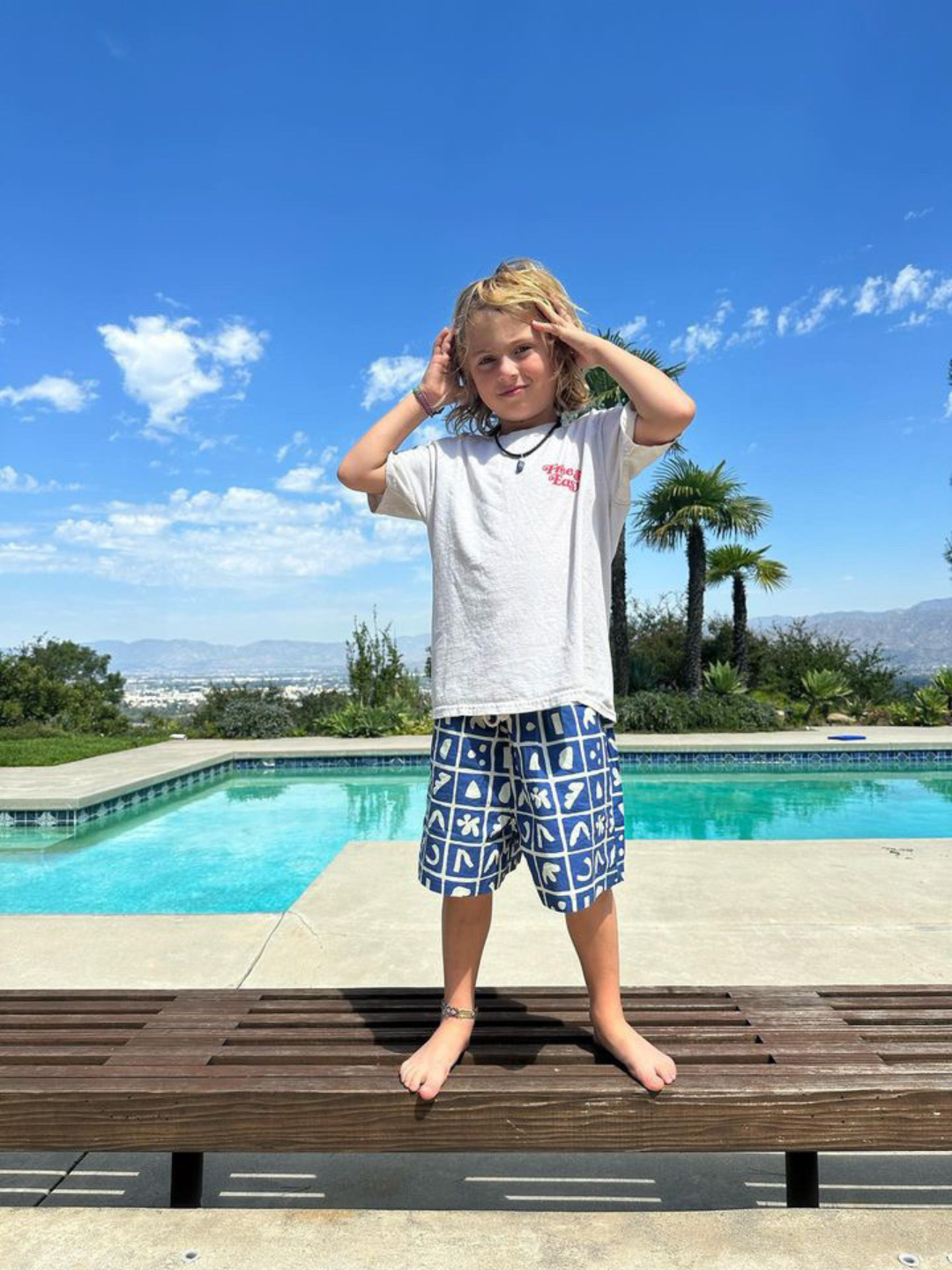 Blue | A Child wearing Palma Shorts In blue with white t-shirt next to a pool