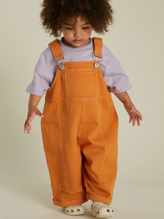 Second image of The BLYTHE MARMALADE DUNGAREE is a slouchy, unisex overall in orange organic cotton twill with adjustable buckle straps and rolled cuffs, shown flat on a white background.