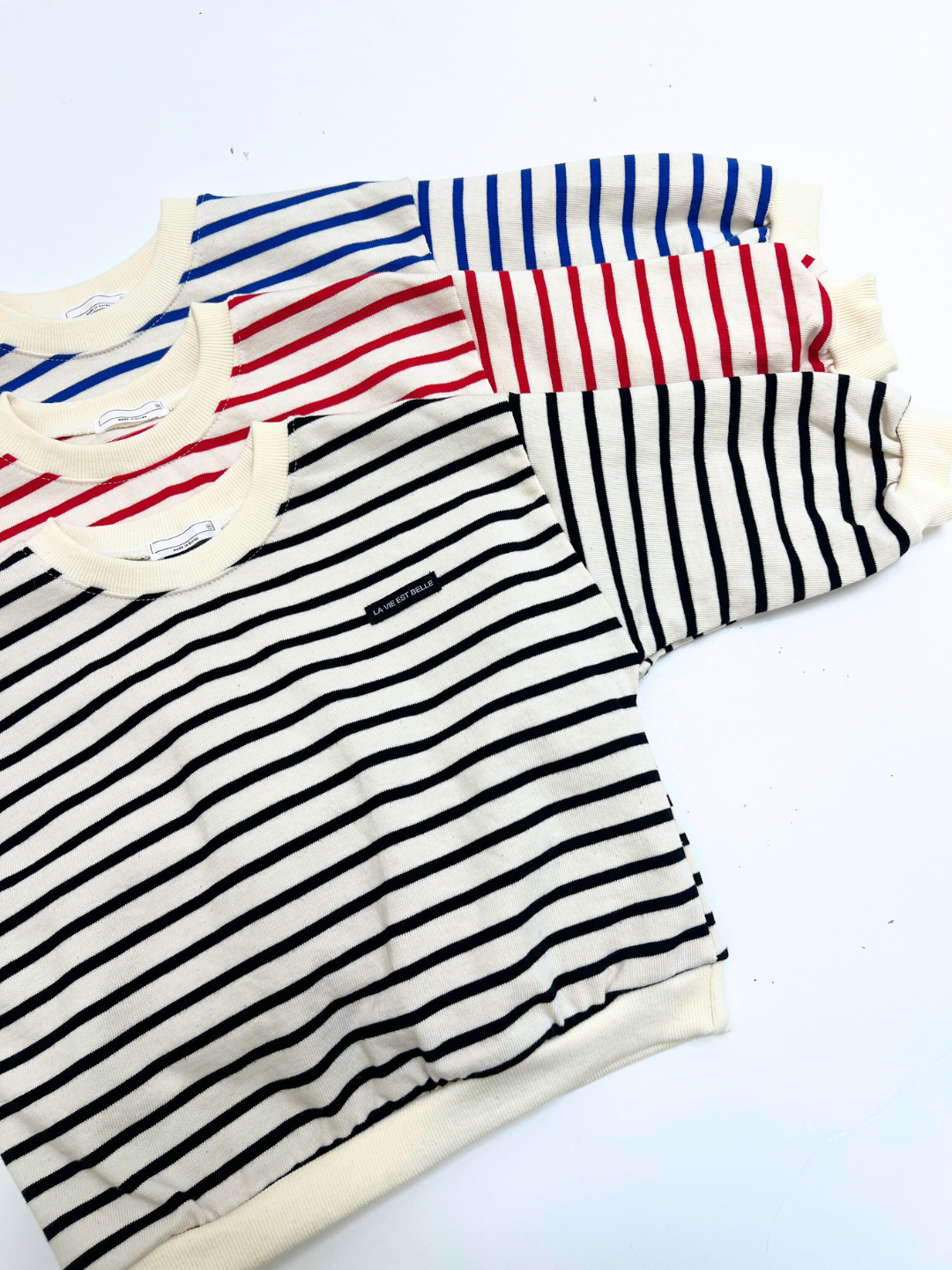 Three BRETON BABY SWEATSHIRTs are laid out side by side, each featuring bold black, red, and blue horizontal stripes on a crisp white background.