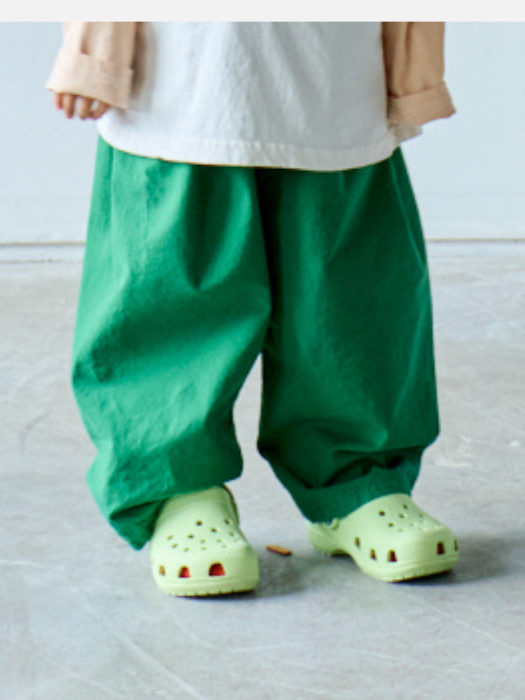 Green | Someone stands casually on a light-colored floor, wearing loose green GARDEN COTTON PANTs and light green clogs.