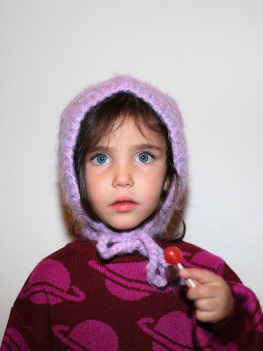 Second image of The POPCORN BONNET is a cozy purple knit bonnet with ear flaps and two long ties, featuring a felted texture against a white background.