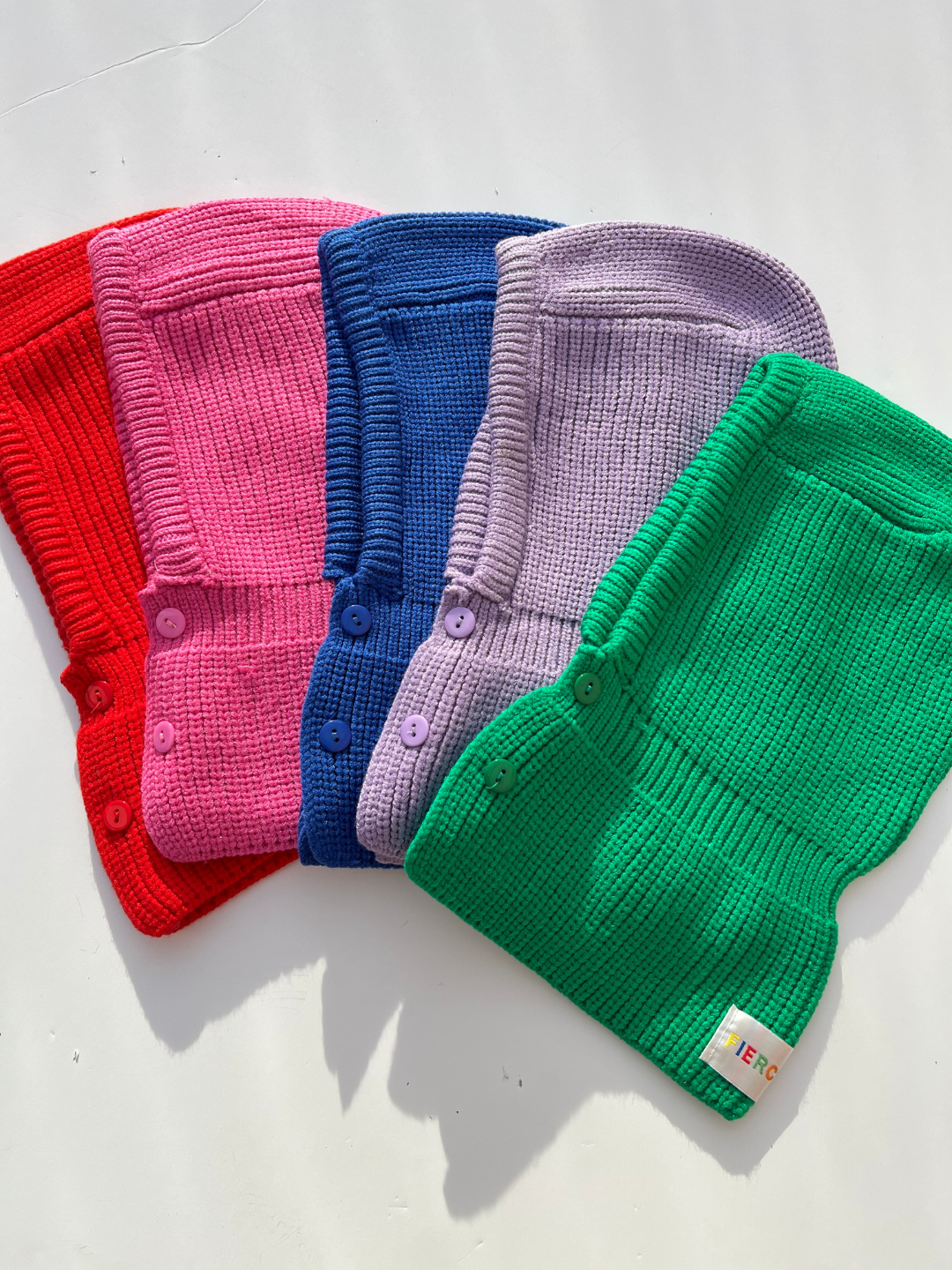 All color of balaclavas laid flat on white background. 