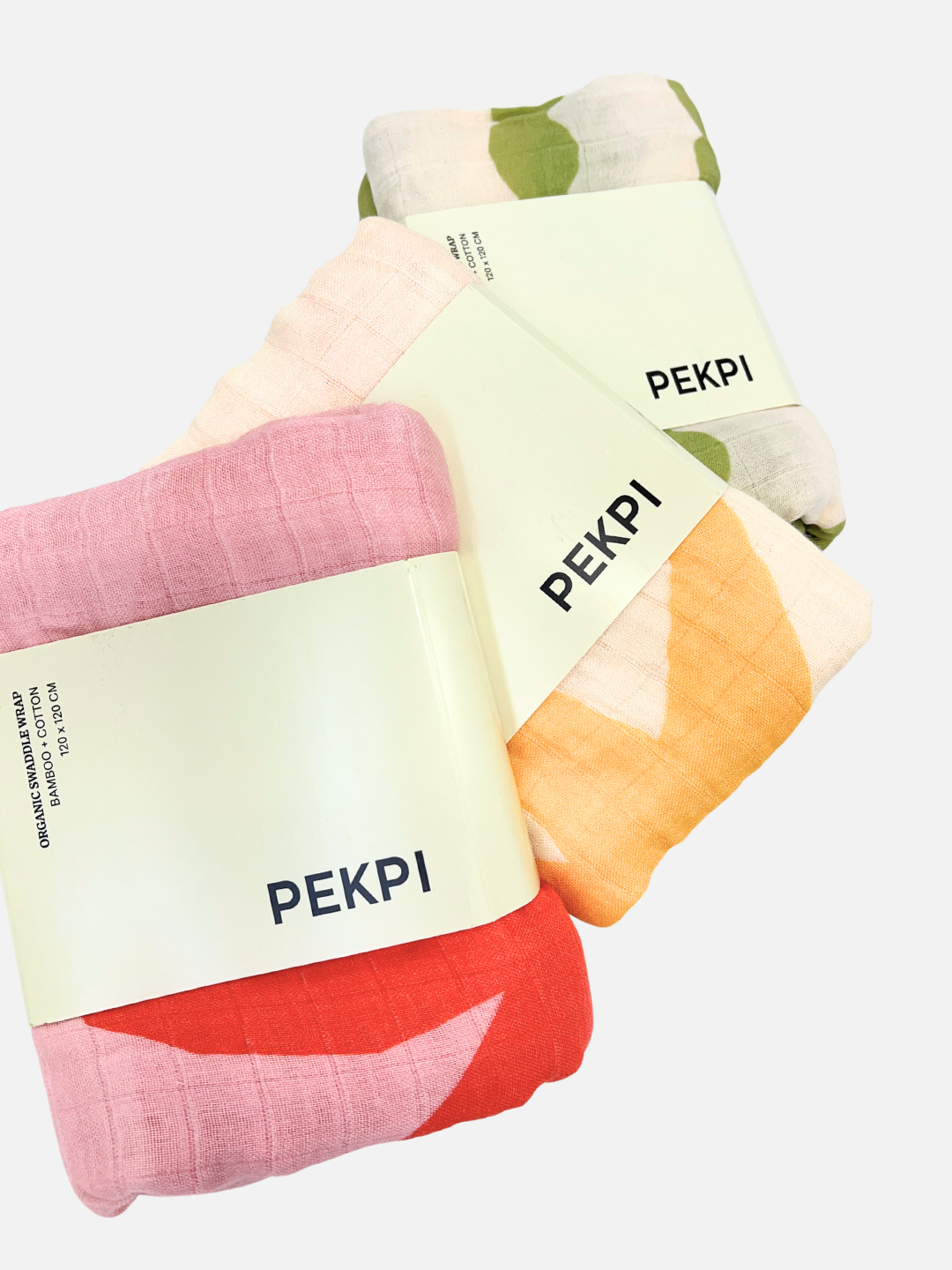 Sunburst | Three folded, patterned cloths in pink, yellow, and green are labeled with "PEKPI" on white bands. These versatile pieces from the ORGANIC BAMBOO SWADDLE WRAP collection can be used as organic cotton swaddles or as a stylish nursing cover.