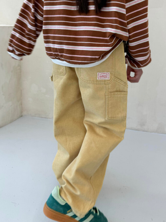 Second image of Ochre | A pair of ochre PIGMENT CARPENTER JEANS for toddlers, featuring an elastic waistband, button-top closure, front pockets, and a wide-leg design in a pigment-dyed denim finish, displayed on a white background.