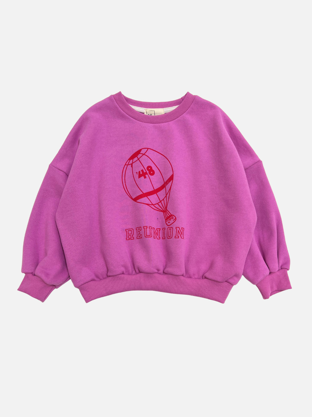 The REUNION SWEATSHIRT in magenta features a bold red outline of a hot air balloon and "REUNION" stylishly printed beneath it on the front.