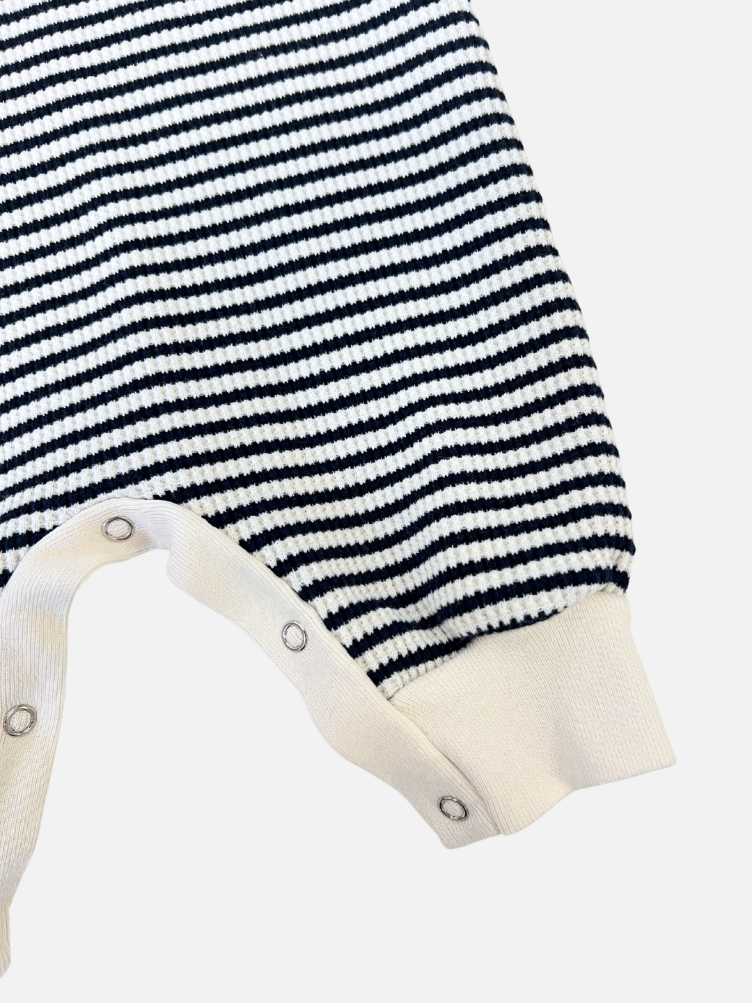 Navy | Close-up of the STRIPE WAFFLE ROMPER SET, featuring a black and white striped baby jumpsuit with snap buttons along the bottom seam, made from soft waffle cotton.