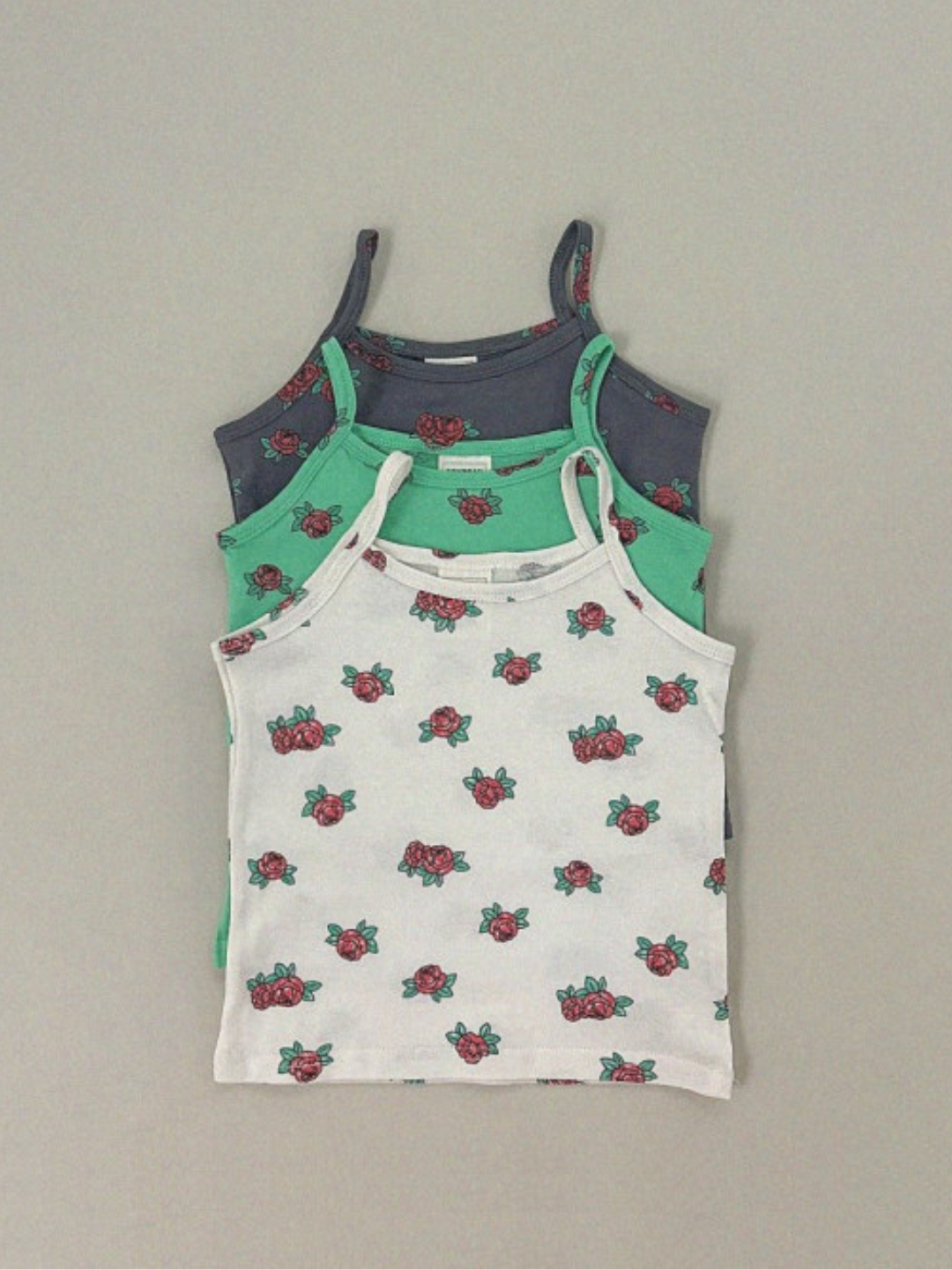 Three color ward of the kids' roses tank tops are laid flat