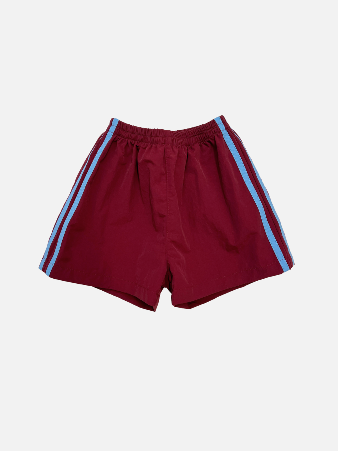 SPRINTER SHORTS in maroon, crafted from performance fabric with an elasticated waist and blue vertical side stripes, shown on a plain white background.