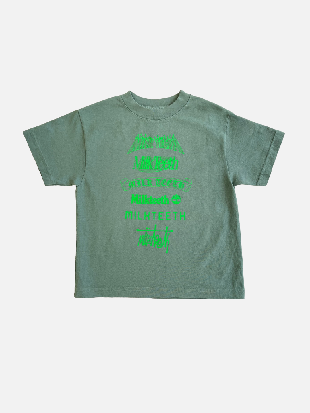 Green | Front view of a kids faded green t-shirt with short sleeves with the text Milk Teeth spelled out in various fonts in neon green ink.