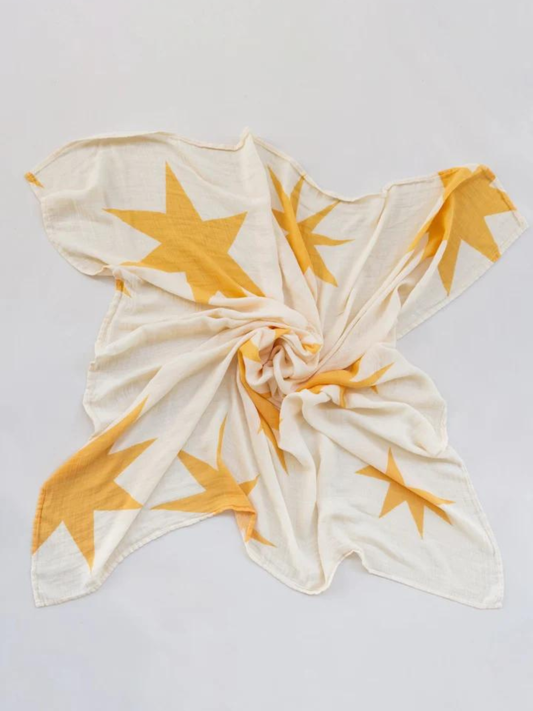 Sunburst | A white fabric with large yellow star patterns is displayed flat, with a twist in the center, perfect for organic bamboo swaddle wraps or even as a stylish nursing cover.