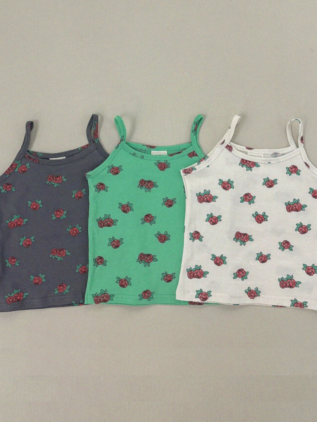 Three color ward of the kids' roses tank tops are laid flat