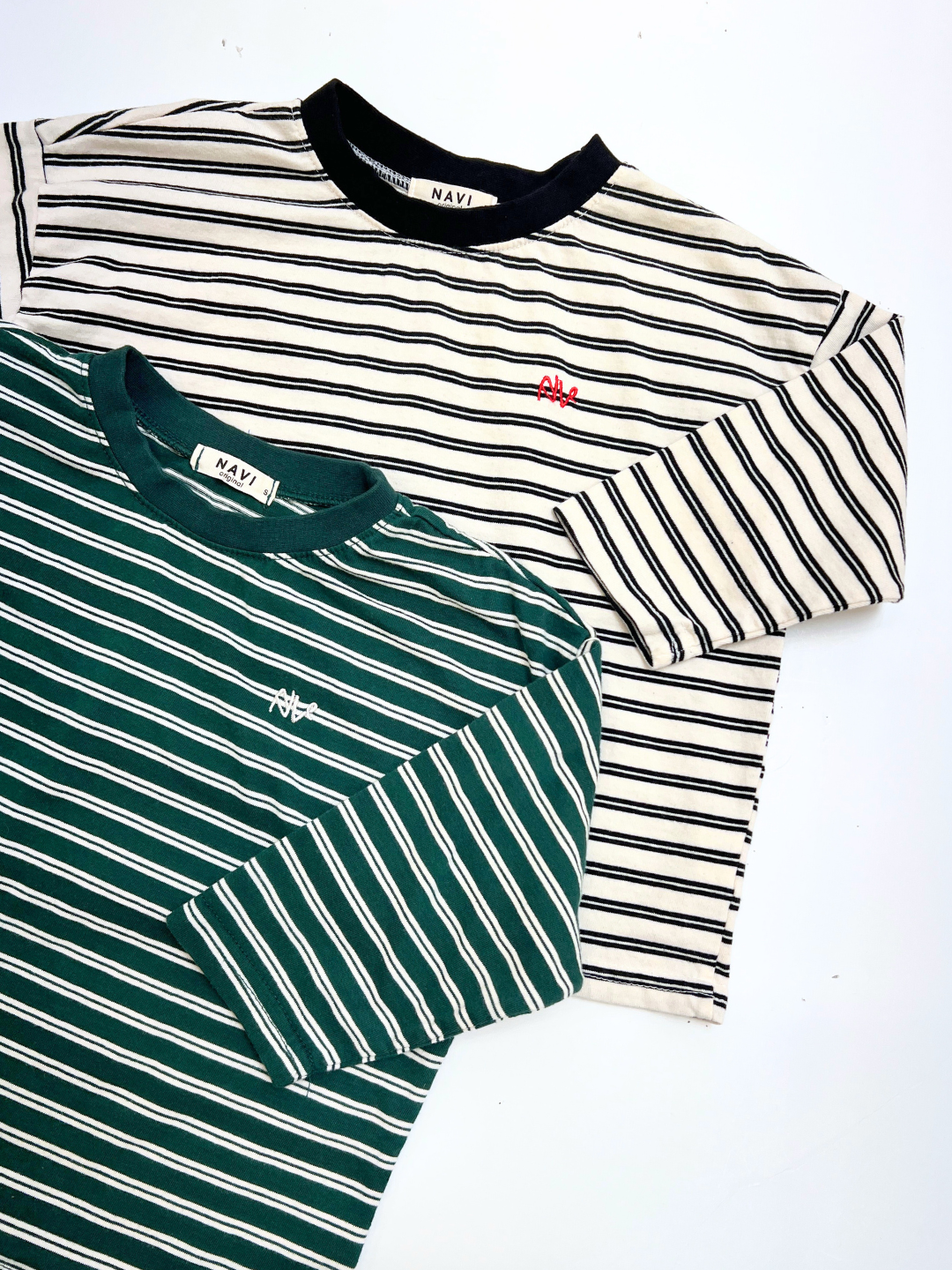 Green | Two CANOE LONGSLEEVE TEE shirts: one white with black stripes, one green with white stripes; both have classic black collars and small embroidered chest logos.