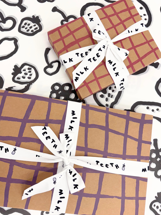 Image of Gift Boxes with plaid brushstrokes wrapping and 'Milk Teeth' ribbon on a patterned background