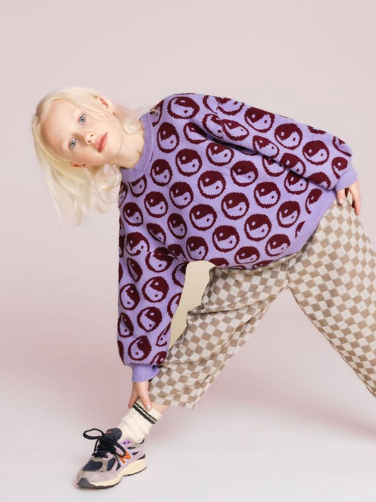 Second image of Violet | The COSMOS SWEATER is a super-soft purple crewneck featuring a red and light purple smiling face pattern throughout the intarsia knit fabric. It also includes a round neckline and ribbed cuffs and hem.