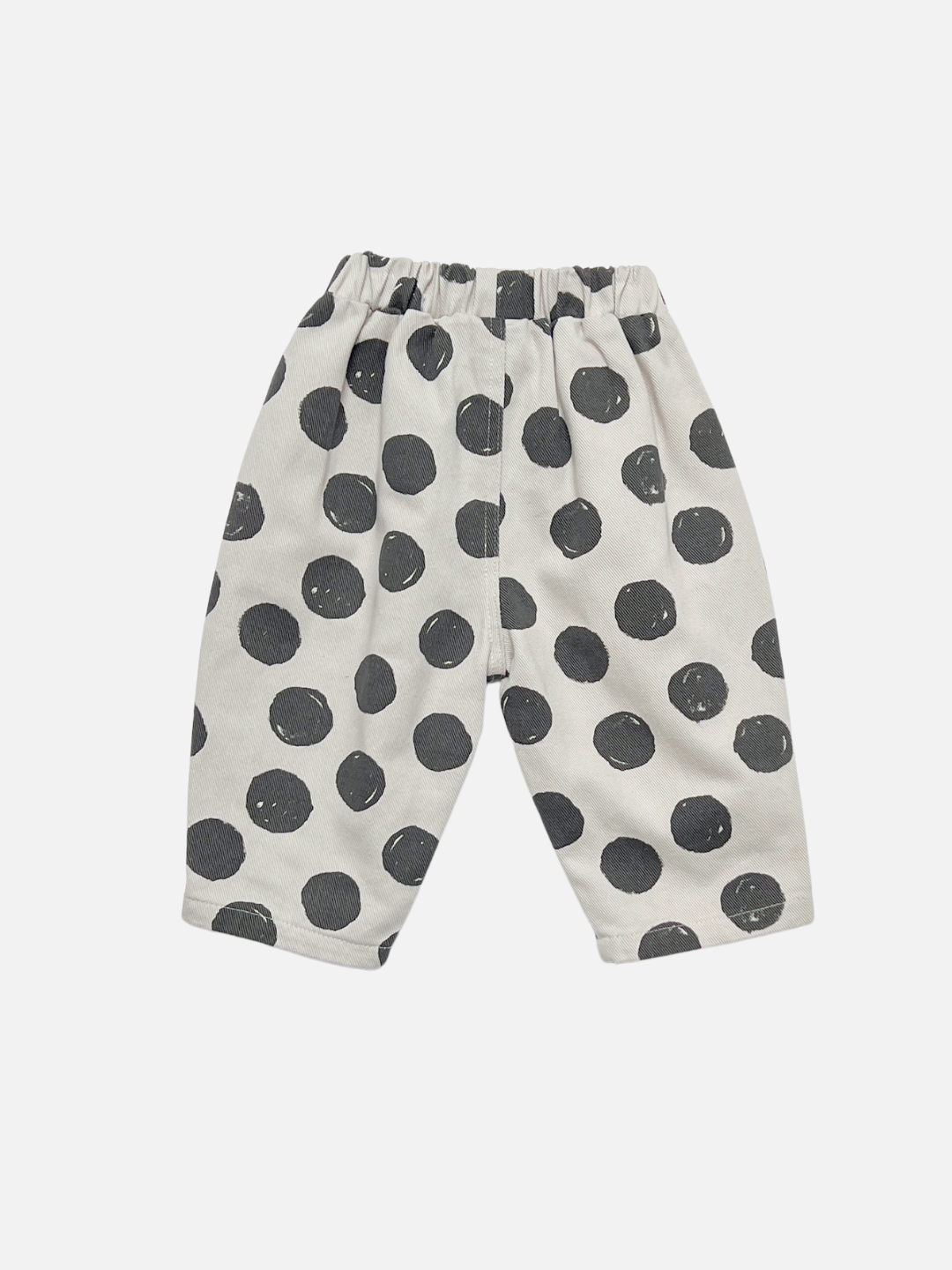 Back view of a pair of toddler pants in an off-white fabric with a large, hand-drawn style black polka dot pattern, shown flat on a light gray background.