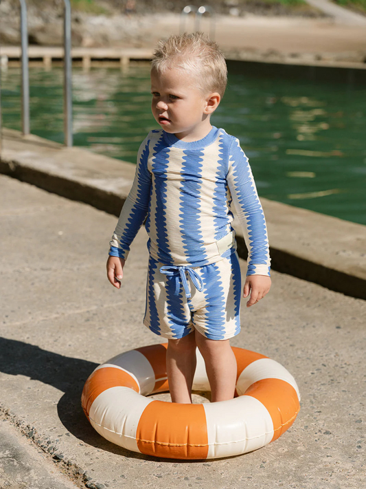 Second image of The KIDS RASHIE TOP features a blue and cream zigzag design, ribbed collar and cuffs, and is made from ribbed recycled fabric. A small front label adds detail. Offers UPF 50+ UV protection for active outdoor days.