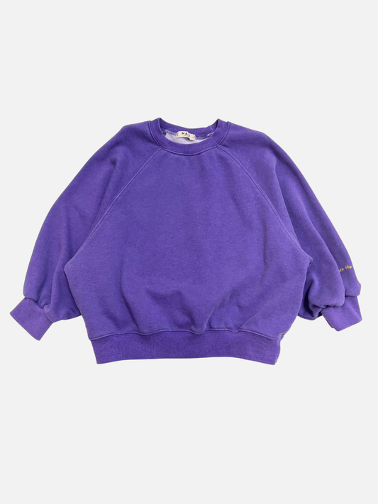 Image of Purple | The PLAYTIME SWEATSHIRT is a vintage-style Korean kids crewneck in plain purple with loose sleeves, ribbed cuffs, collar, and hem. Made from garment-dyed cotton and shown against a white background.