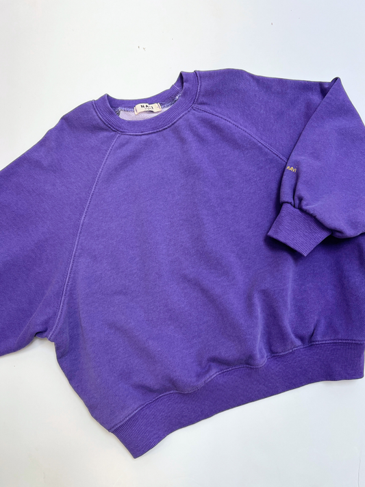 Second image of Purple | The PLAYTIME SWEATSHIRT is a vintage-style Korean kids crewneck in plain purple with loose sleeves, ribbed cuffs, collar, and hem. Made from garment-dyed cotton and shown against a white background.