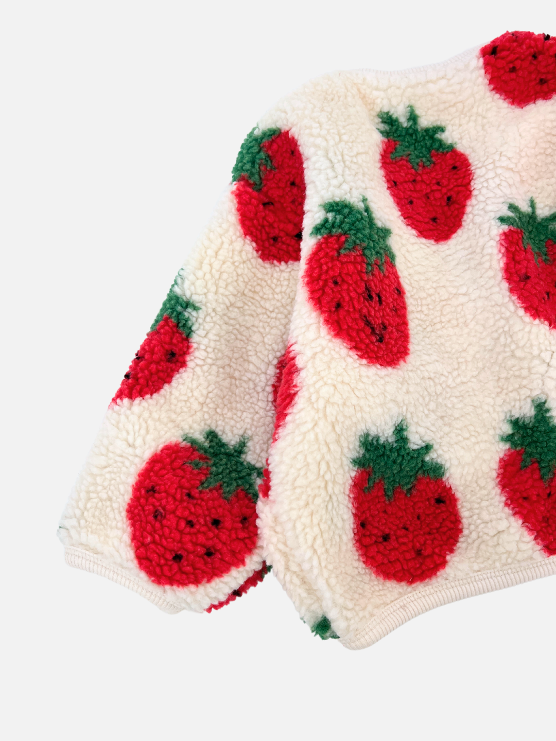 Experience the delight of the STRAWBERRY SHERPA JACKET, a charming white fleece sweater adorned with vibrant red and green strawberry patterns. Designed by the Korean kids brand Hanab, this plush sherpa fleece jacket offers both warmth and style for your little one.